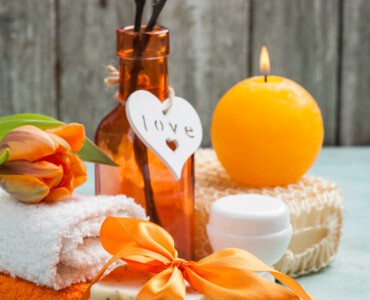 Spa composition with handmade organic soap and orange bow. Cosmetics on blue concrete table close-up