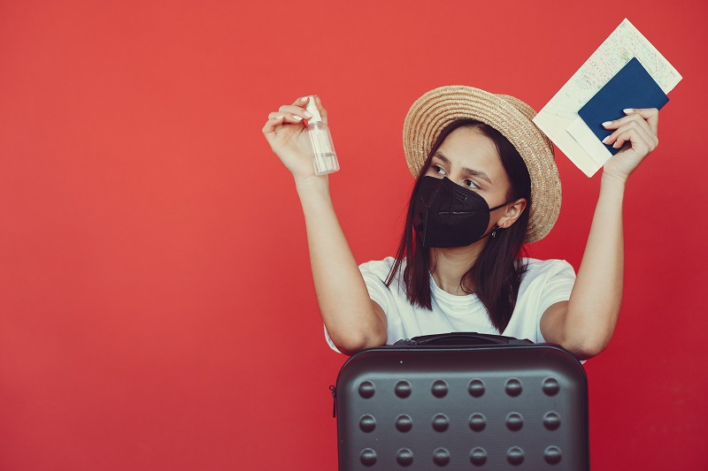 Vacation theme. Girl in a studio. Person on a red background. Canceled trip because of coronavirus.