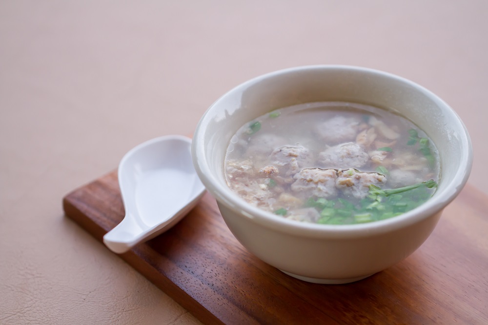 Rice boiled with pork, garlic and coriander bowl on wooden and spoon.